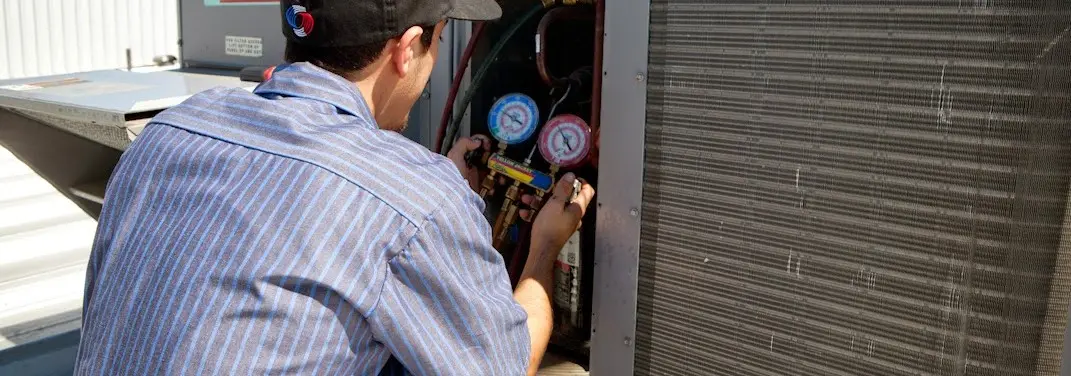 HVAC technician servicing a condenser unit in Kahaluu